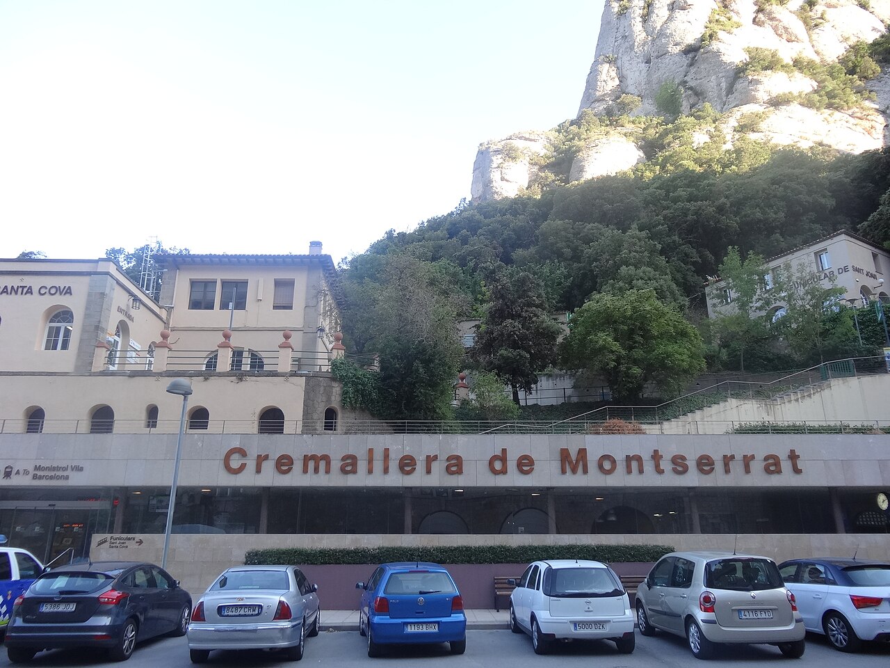 Die Bergstation der Zahnradbahn Cremallera de Montserrat am Kloster, mit Schildern nach Monistrol Vila und Barcelona und den Felswänden dahinter